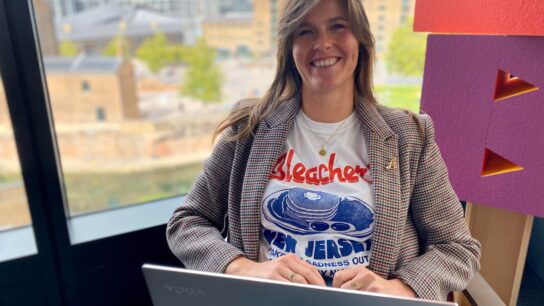 Person sitting down smiling over a laptop