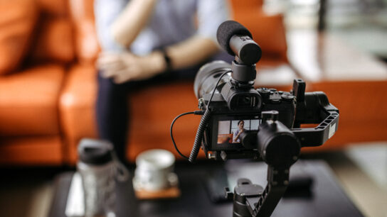 Video camera  recording someone sat talking on a sofa